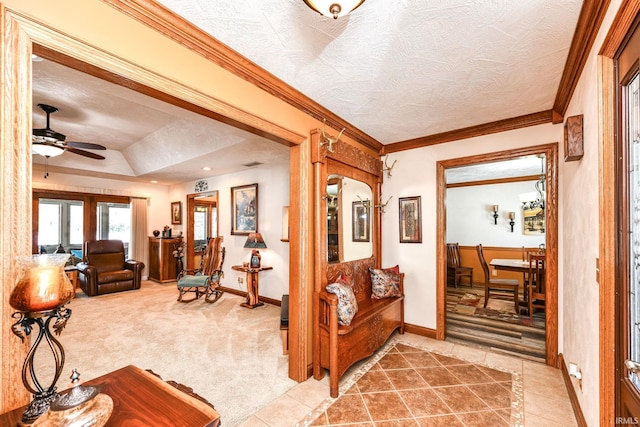 interior space with ceiling fan, a raised ceiling, crown molding, a textured ceiling, and carpet