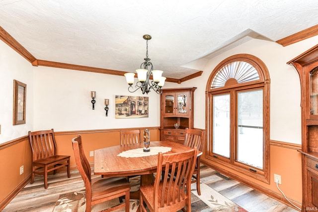 dining area featuring a textured ceiling, an inviting chandelier, light hardwood / wood-style flooring, and crown molding