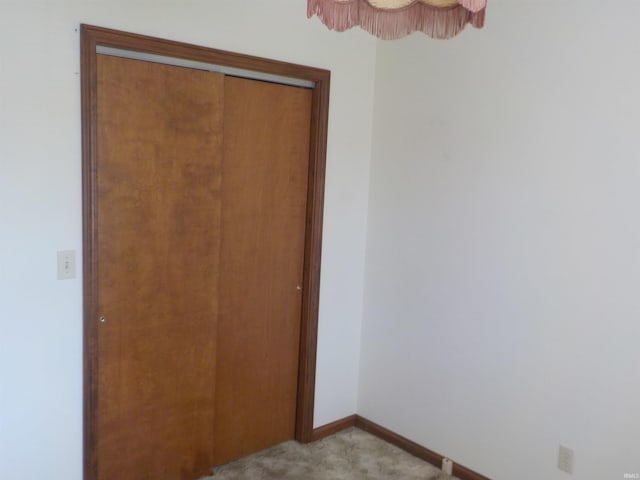 unfurnished bedroom with light colored carpet and a closet