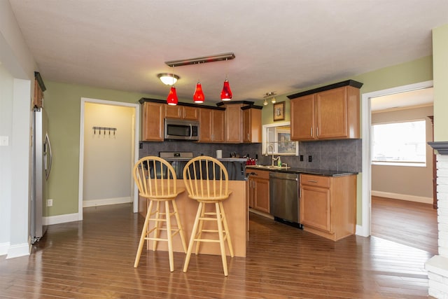 kitchen featuring a kitchen breakfast bar, sink, appliances with stainless steel finishes, tasteful backsplash, and dark hardwood / wood-style flooring