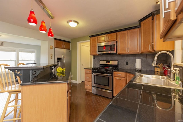 kitchen featuring pendant lighting, a breakfast bar, sink, appliances with stainless steel finishes, and dark hardwood / wood-style flooring