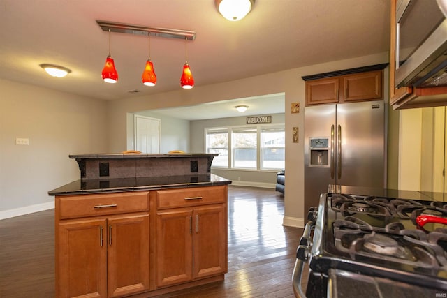 kitchen featuring dark hardwood / wood-style flooring, stainless steel appliances, and hanging light fixtures