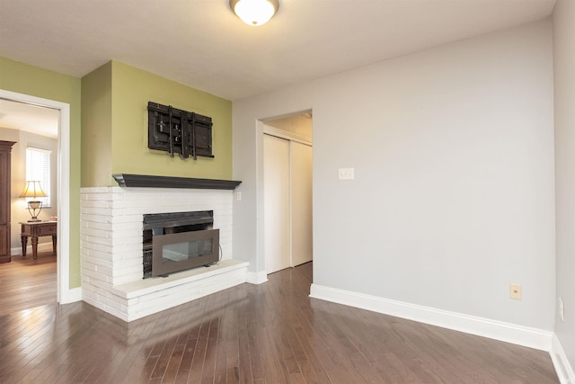 unfurnished living room featuring a fireplace and dark wood-type flooring