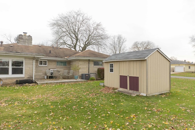 rear view of property with a patio, a yard, central AC, and a storage shed