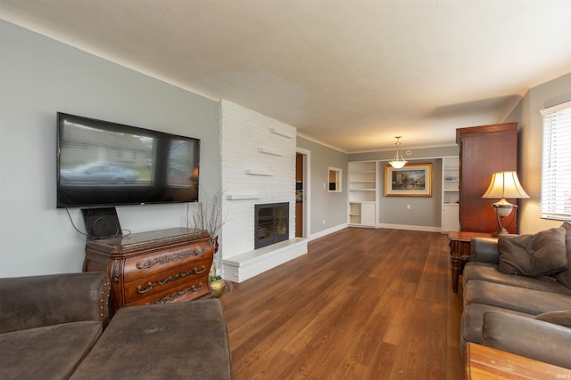 living room featuring a fireplace, built in shelves, and dark hardwood / wood-style flooring