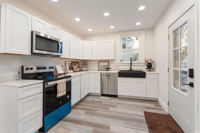 kitchen featuring white cabinets, appliances with stainless steel finishes, light hardwood / wood-style flooring, and sink