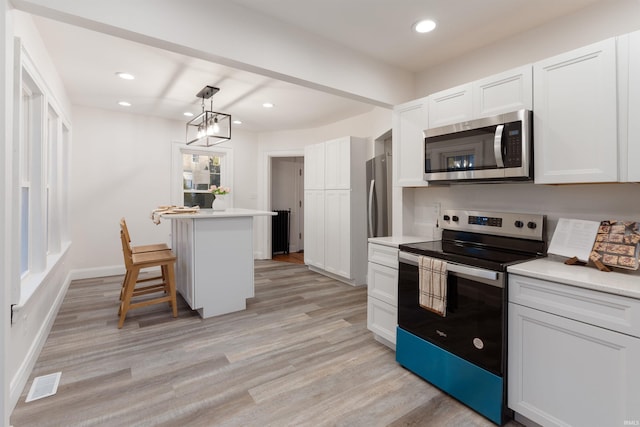 kitchen featuring a breakfast bar, pendant lighting, stainless steel appliances, and white cabinets