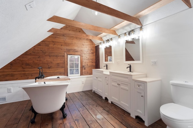 bathroom with a washtub, vanity, hardwood / wood-style flooring, vaulted ceiling with beams, and toilet