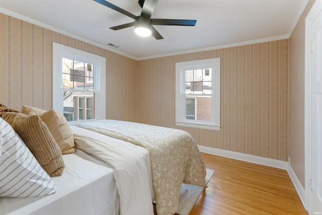 bedroom with multiple windows, ceiling fan, crown molding, and hardwood / wood-style floors