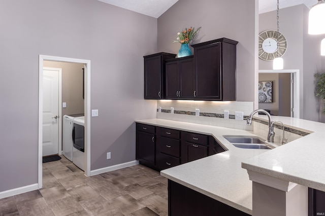 kitchen with washer and dryer, pendant lighting, kitchen peninsula, and sink