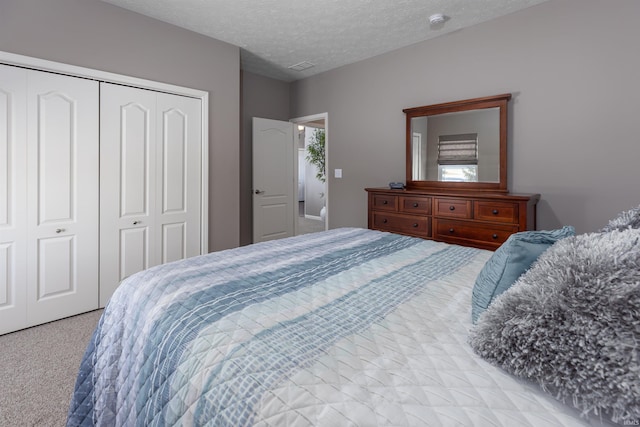 bedroom with a textured ceiling, light colored carpet, and a closet