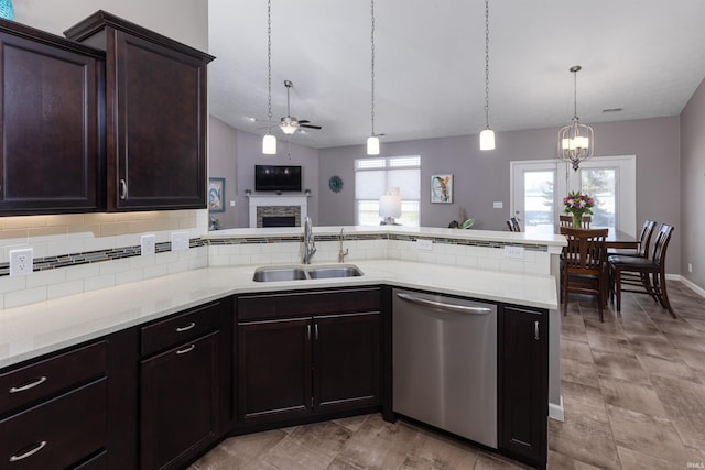 kitchen featuring stainless steel dishwasher, ceiling fan with notable chandelier, sink, decorative light fixtures, and a fireplace