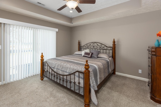 carpeted bedroom featuring a textured ceiling, a tray ceiling, and ceiling fan