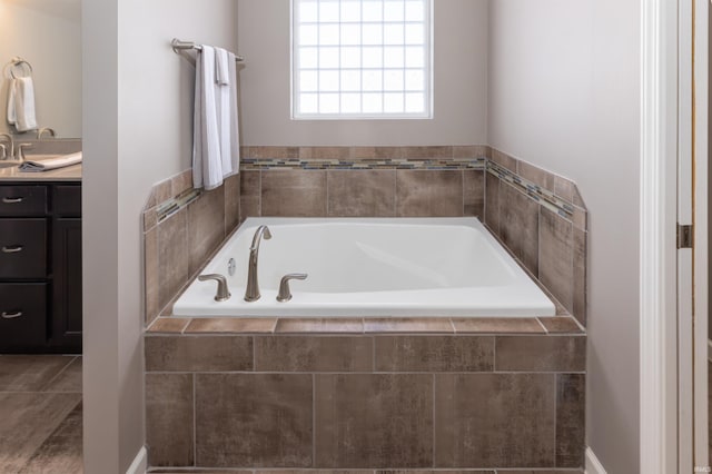 bathroom featuring vanity and tiled bath