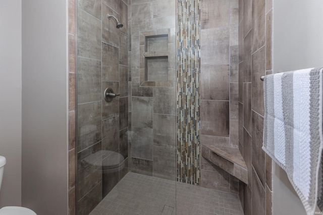 bathroom with toilet and a tile shower