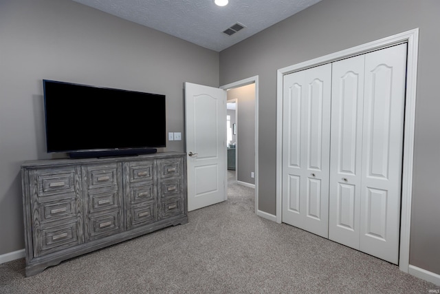 carpeted bedroom with a textured ceiling and a closet