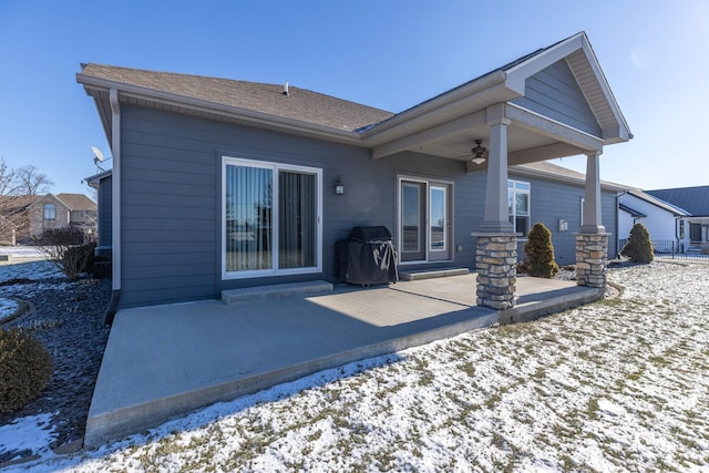 snow covered back of property featuring ceiling fan and a patio area