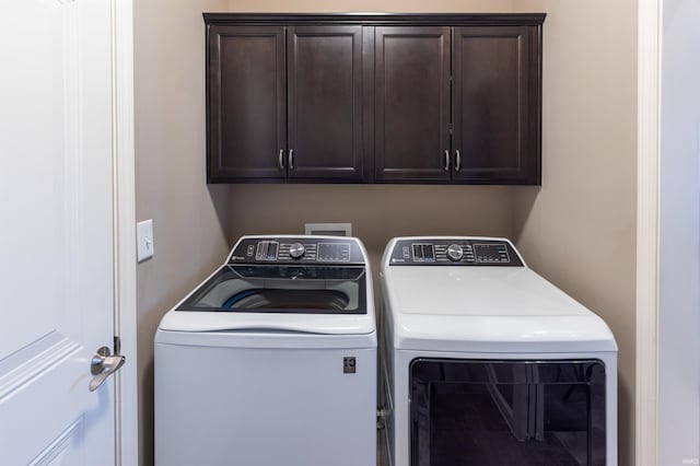 clothes washing area with cabinets and washing machine and clothes dryer