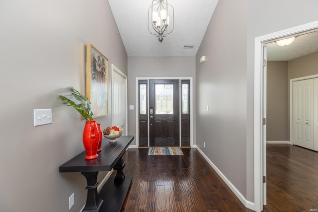 foyer featuring a textured ceiling, dark wood-type flooring, and a chandelier