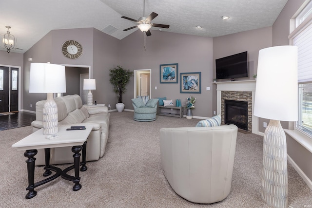 living room featuring carpet, lofted ceiling, ceiling fan with notable chandelier, a fireplace, and a textured ceiling