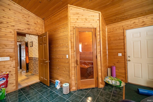 interior space with wooden walls, tile patterned flooring, and vaulted ceiling