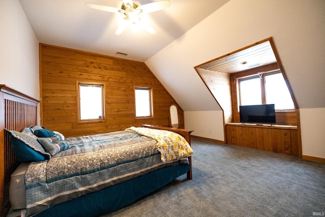 carpeted bedroom featuring ceiling fan, wood walls, and vaulted ceiling