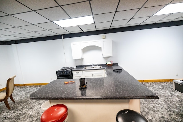 kitchen featuring carpet flooring, white cabinetry, sink, a drop ceiling, and kitchen peninsula