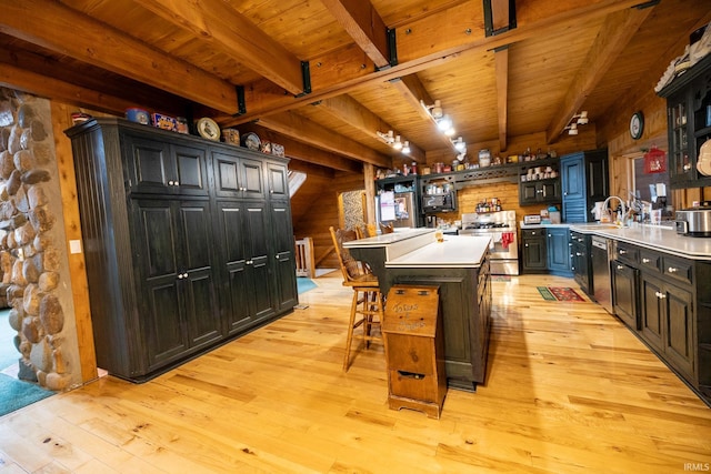 kitchen with beam ceiling, a breakfast bar, a kitchen island, and appliances with stainless steel finishes