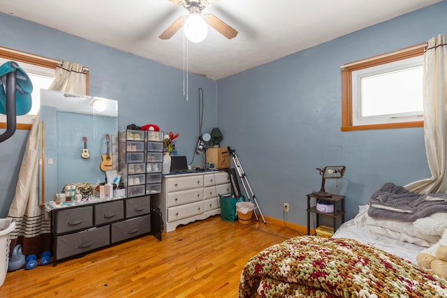 bedroom featuring ceiling fan, multiple windows, and light hardwood / wood-style flooring