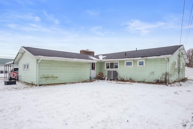 snow covered back of property featuring central AC