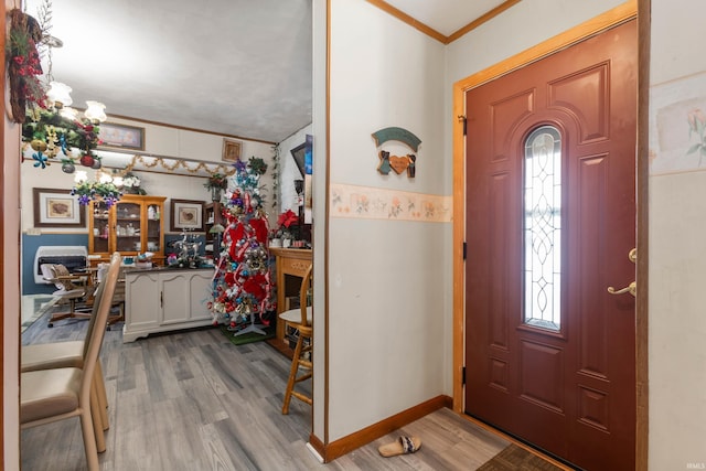 entryway with ornamental molding and light hardwood / wood-style flooring