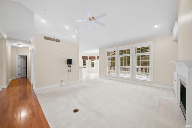 unfurnished living room featuring ceiling fan with notable chandelier, ornamental molding, a wealth of natural light, and vaulted ceiling