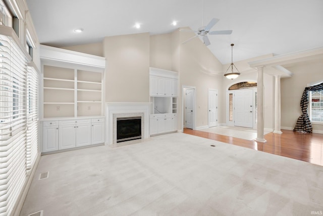 unfurnished living room featuring built in shelves, ceiling fan, plenty of natural light, and a fireplace