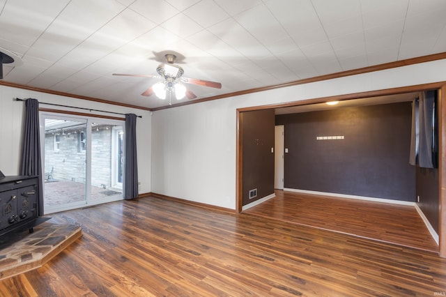 unfurnished living room with ceiling fan, dark hardwood / wood-style flooring, a wood stove, and crown molding