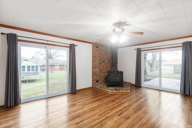 unfurnished living room with hardwood / wood-style flooring, ceiling fan, a healthy amount of sunlight, and a wood stove