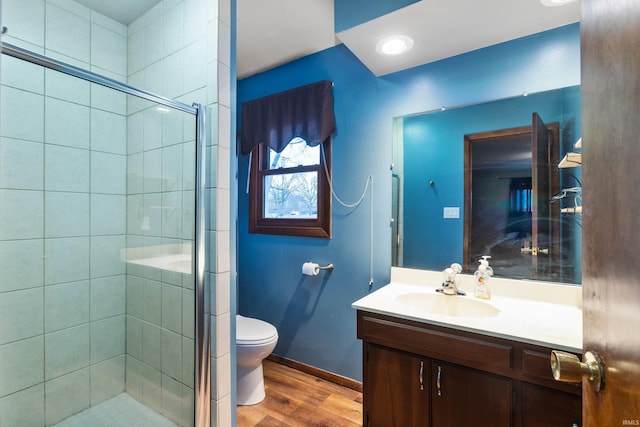 bathroom with hardwood / wood-style floors, vanity, toilet, and a shower with door