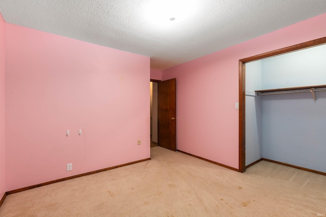 unfurnished bedroom with a textured ceiling, light colored carpet, and a closet