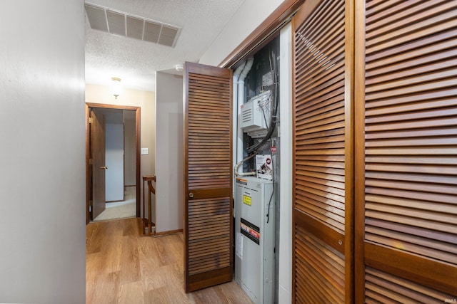 hall featuring a textured ceiling and light hardwood / wood-style flooring