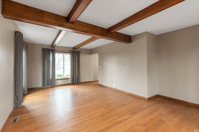 unfurnished room featuring beam ceiling, light hardwood / wood-style floors, and a textured ceiling