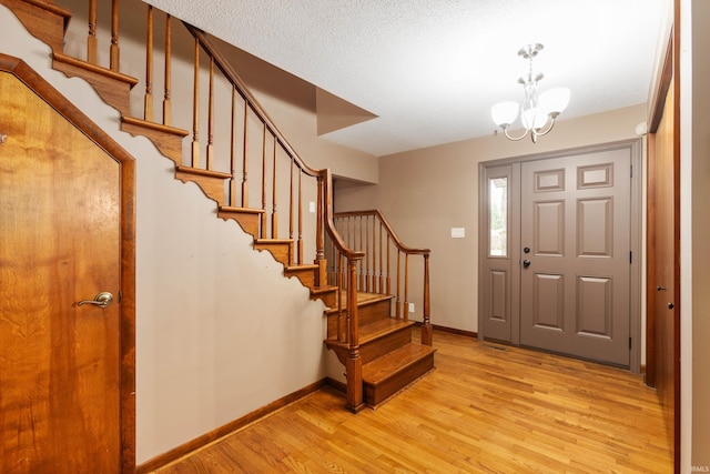 foyer featuring a textured ceiling, a notable chandelier, and light wood-type flooring