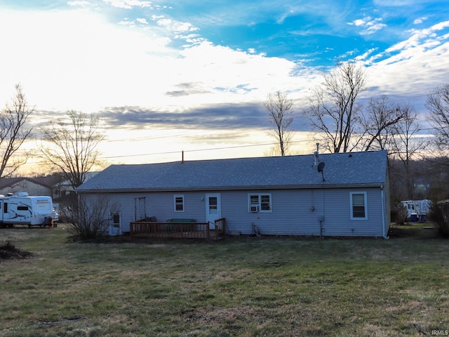 back house at dusk featuring a lawn and a wooden deck