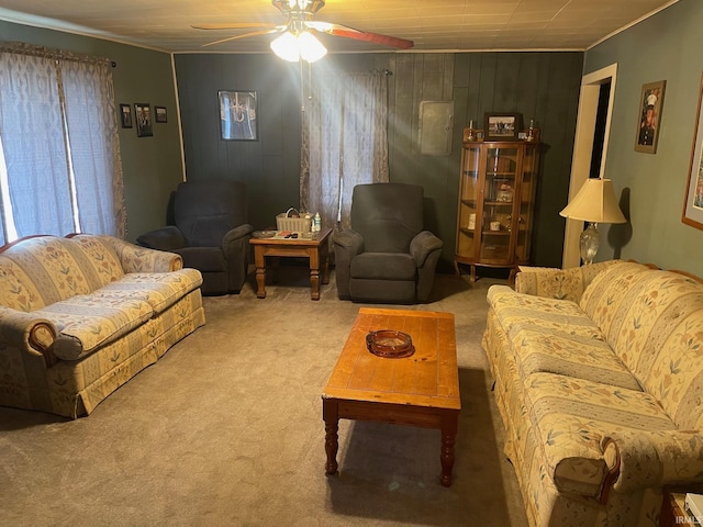 living room with ceiling fan, wood walls, carpet floors, and crown molding