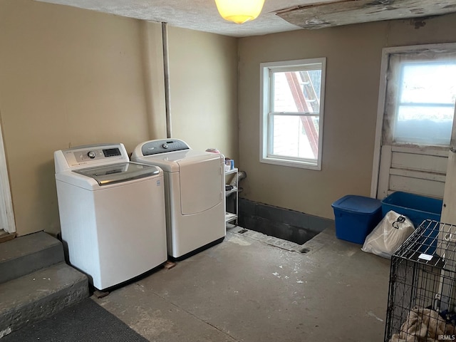 washroom with independent washer and dryer, a textured ceiling, and a healthy amount of sunlight