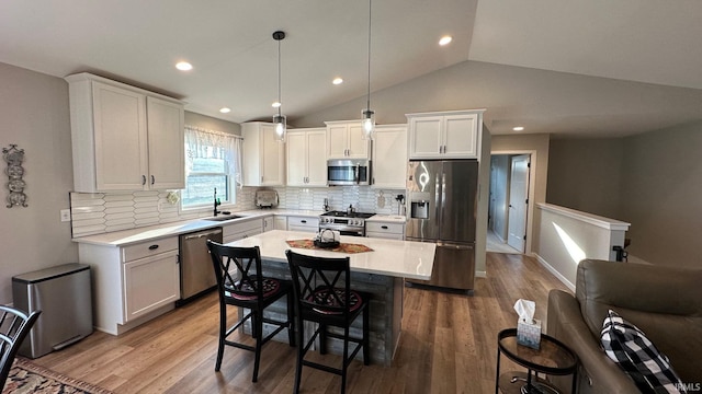 kitchen with tasteful backsplash, stainless steel appliances, sink, white cabinets, and hanging light fixtures