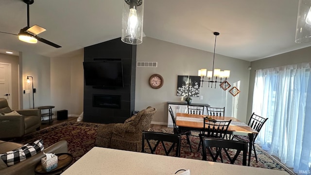 dining space with a fireplace, ceiling fan with notable chandelier, and lofted ceiling