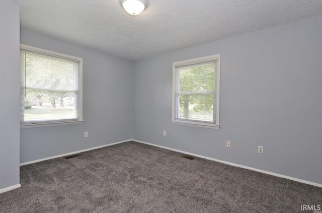 unfurnished room with dark colored carpet and a textured ceiling