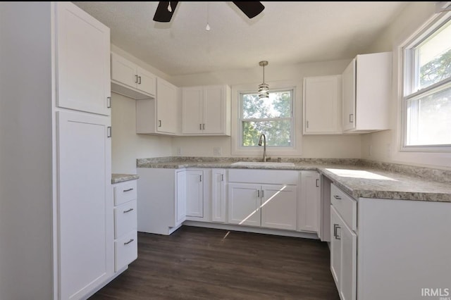 kitchen with decorative light fixtures, white cabinetry, sink, and dark wood-type flooring