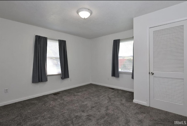 carpeted empty room with a textured ceiling