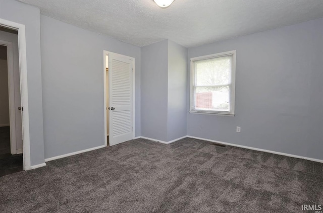 interior space featuring dark carpet and a textured ceiling