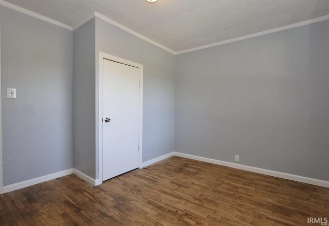 empty room with a textured ceiling, crown molding, and dark wood-type flooring